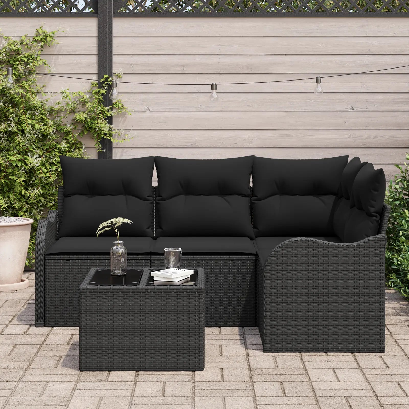 Coussins moelleux sur canapé de jardin tressé noir.